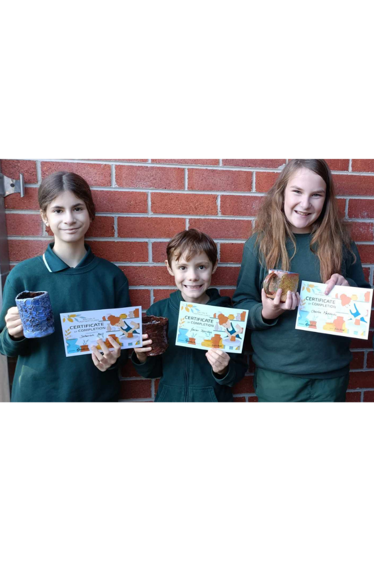Three students holding their pottery and certificate