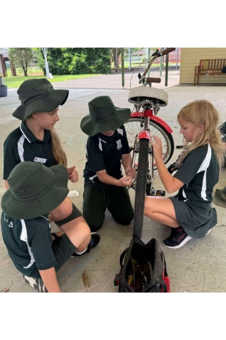 Four primary aged students fixing a pushbike